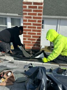 A focused technician uses a power tool for precise adjustments to the chimney flashing, ensuring a snug fit against the red brick structure
